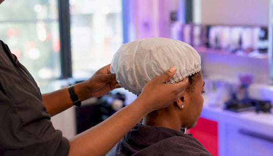 Stylist placing steam bonnet on client's hair