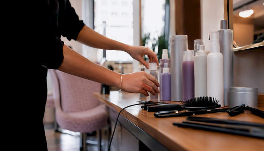 Hands arranging salon haircare products on counter