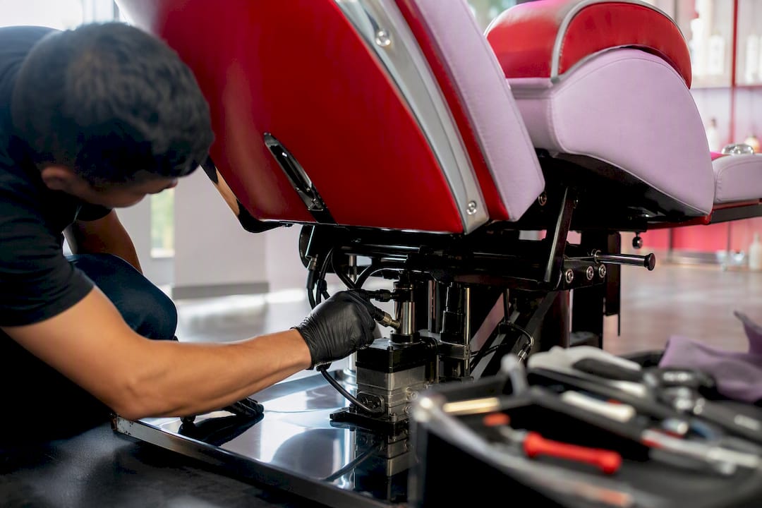 Technician servicing salon chair hydraulic pump